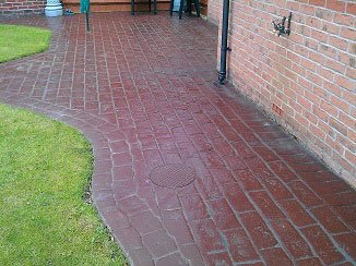 Photo of imprinted concrete surface in Codsall, Shropshire before cleaning showing faded colours and dirt filled cracks.