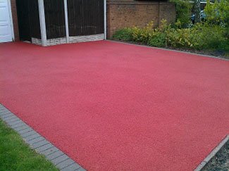 Photo of vivid clean and resealed red tarmac driveway.